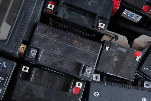 Das Bild zeigt alte Auto- und Motorradbatterien, die in einer Paloxe gesammelt wurden.