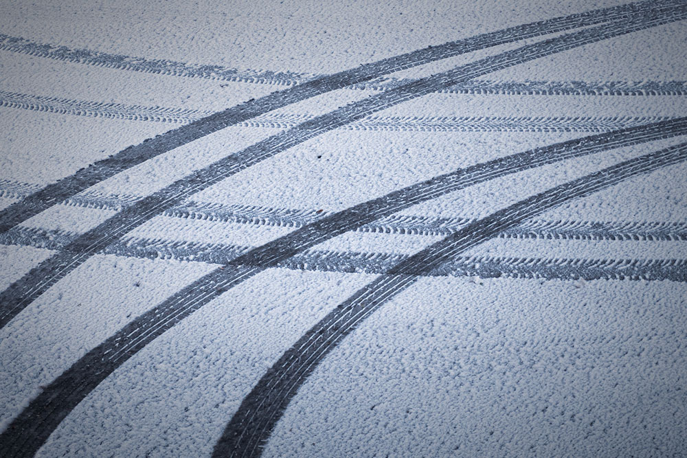 Das Bild zeigt Reifenspuren im frischen Schnee