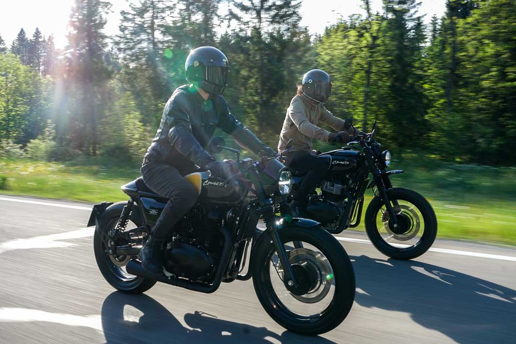 Teaserbild – Einsatzgebiet Motorradbatterien Das Bild zeigt 2 Motorradfahrer, welche bei sonnigem Wetter durch einen Wald fahren.