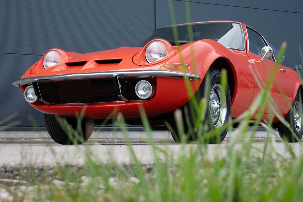 Teaserbild Einsatzgebiet Auto-Batterien Das Bild zeigt einen orang-farbenen Oldtimer vor einem grauen Hintergrund.